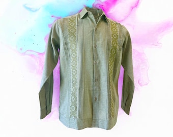 May include: A long-sleeved, button-down shirt in a muted green hue. The shirt features intricate embroidered panels down the front and on the sleeves, with a floral pattern. The shirt is made of a textured fabric.