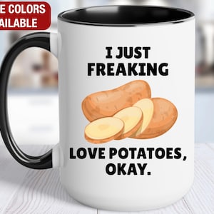 May include: White ceramic mug with a black handle and rim, featuring the text "I JUST FREAKING LOVE POTATOES, OKAY." and a graphic of potatoes. The mug has a red rectangle that says "MORE COLORS AVAILABLE".