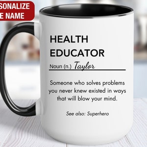 May include: White ceramic mug with a black handle and rim. The mug has a black and white design that reads "HEALTH EDUCATOR Noun (n.) Taylor Someone who solves problems you never knew existed in ways that will blow your mind. See also: Superhero"