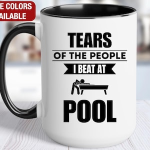 May include: White ceramic coffee mug with a black rim and handle. The mug features a black and white graphic that says "Tears of the people I beat at pool".