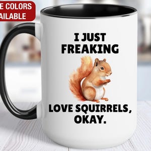 May include: White ceramic mug with a black handle and rim. The mug features a watercolor illustration of a squirrel and the text "I JUST FREAKING LOVE SQUIRRELS, OKAY." The top left corner has a red banner that says "MORE COLORS AVAILABLE."