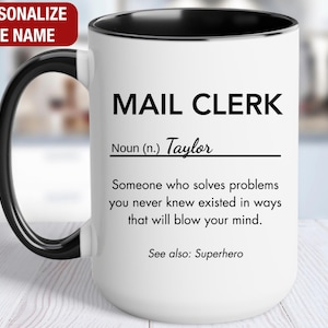 May include: White ceramic mug with a black rim and handle. The mug has a black and white design that reads "MAIL CLERK Noun (n.) Taylor Someone who solves problems you never knew existed in ways that will blow your mind. See also: Superhero"