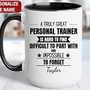 May include: White ceramic coffee mug with a black rim and handle. The mug has a black design that reads "A truly great personal trainer is hard to find, difficult to part with and impossible to forget." The name "Taylor" is printed below the design.