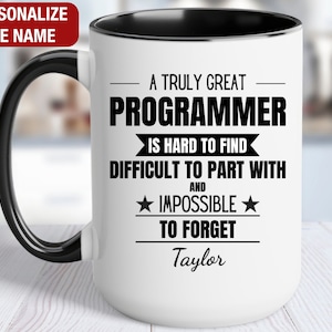 May include: White ceramic mug with a black handle and black rim. The mug has a black inscription that reads "A truly great programmer is hard to find, difficult to part with and impossible to forget." The name "Taylor" is printed below the inscription.