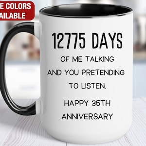 May include: White ceramic coffee mug with a black handle and black rim. The mug has black text that reads "12775 DAYS OF ME TALKING AND YOU PRETENDING TO LISTEN. HAPPY 35TH ANNIVERSARY".