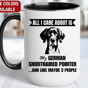 May include: White ceramic coffee mug with a black handle and rim. The mug has a black and white graphic of a German Shorthaired Pointer dog with the text "All I care about is my German Shorthaired Pointer...and like maybe 3 people."