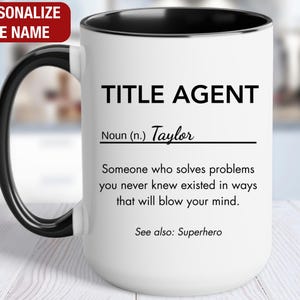 May include: White ceramic coffee mug with a black rim and handle. The mug has black text that reads "TITLE AGENT" and "Noun (n.) Taylor" followed by a definition. The definition reads "Someone who solves problems you never knew existed in ways that will blow your mind." Below the definition is the text "See also: Superhero."