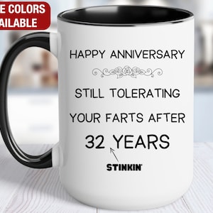 May include: White ceramic coffee mug with a black handle and black rim. The mug has a funny anniversary message that reads "Happy Anniversary Still Tolerating Your Farts After 32 Years Stinkin'"