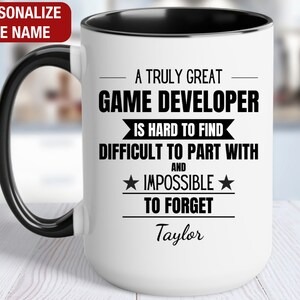 May include: White coffee mug with a black handle and black rim. The mug has black text that reads "A truly great game developer is hard to find, difficult to part with and impossible to forget." The text "Taylor" is printed below the text.