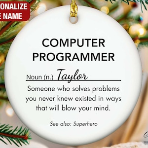 May include: A white ceramic Christmas ornament with gold hanging string. The ornament has the text "COMPUTER PROGRAMMER" and a definition. The name "Taylor" is written below the definition.