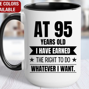 May include: White ceramic coffee mug with a black rim and handle. The mug has black text that reads "At 95 Years Old I Have Earned The Right To Do Whatever I Want."