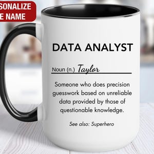 May include: White ceramic mug with a black handle and rim. The mug features the text "DATA ANALYST" and a definition, including the name "Taylor". The top left corner has the text "PERSONALIZE THE NAME" in a red box.