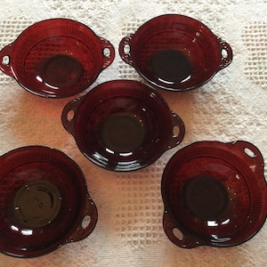 May include: Five red glass bowls with handles. The bowls have a ribbed design and are perfect for serving snacks or desserts.