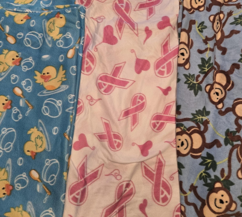 K&ouml;nnte beinhalten: Drei Stoffe mit Mustern werden gezeigt. Einer ist hellblau mit gelben Entenk&uuml;ken und L&ouml;ffeln. Der zweite ist wei&szlig; mit rosa Schleifen und Herzen. Der dritte ist hellblau mit braunen Affen und gr&uuml;nen Bl&auml;ttern.
