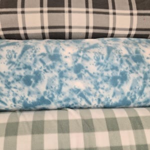 K&ouml;nnte beinhalten: Drei Rollen aus Fleece-Stoff. Die obere Rolle hat ein schwarz-wei&szlig;-graues Karomuster. Die mittlere Rolle hat ein blau-wei&szlig;es Spritzmuster. Die untere Rolle zeigt ein wei&szlig;-gr&uuml;nes Vichy-Muster.