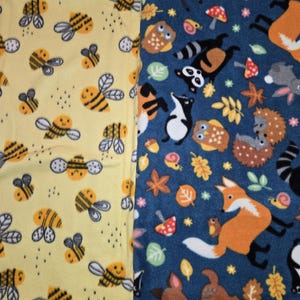 K&ouml;nnte beinhalten: Zwei Fleece-Stoffe mit unterschiedlichen Mustern. Einer ist gelb mit l&auml;chelnden Bienen. Der andere ist blau mit Waldtieren wie F&uuml;chsen, Rehen, Eulen und Waschb&auml;ren. Die Stoffe sind wahrscheinlich f&uuml;r Decken oder andere Textilprojekte.