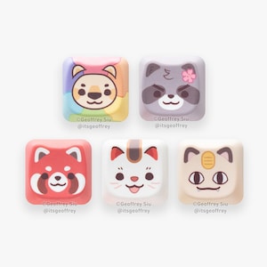 May include: Five colorful keycaps with animal faces. The keycaps are square and have rounded edges. The animals are a red panda, a raccoon, a cat, a cat, and a lion. The keycaps are designed to be used on a mechanical keyboard.