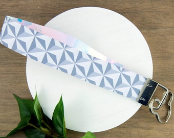 May include: A gray and white geometric patterned key chain with a silver heart-shaped key ring.