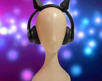May include: A mannequin head with black headphones and a black headband with two triangular, pointed accents. The background is a gradient of purple and blue with blurred white and blue circles.