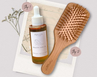 Könnte beinhalten: Eine Flasche Healthy Hair Oil und eine Holzbürste werden vor einem Hintergrund im Vintage-Stil präsentiert. Die Ölflasche hat ein weißes Etikett mit einer Frauensilhouette und den Worten "Impeccably Pure" und "Healthy Hair Oil". Die Holzbürste ist hellbraun.