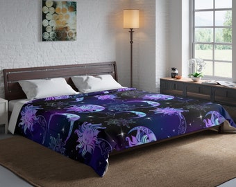 May include: A dark blue and purple comforter with a repeating pattern of suns and moons. The suns and moons are stylized and have a celestial design. The comforter is on a bed with white pillows.