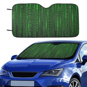 May include: A black and green car sunshade featuring a digital rain pattern. The sunshade is displayed on the windshield of a blue car. The pattern consists of vertical lines of green characters resembling binary code.