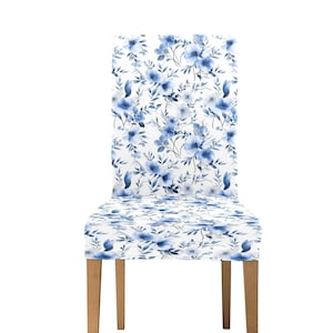 May include: A white chair cover with a blue floral pattern. The cover is made of a soft, stretchy fabric and fits snugly over the chair. The chair has wooden legs.