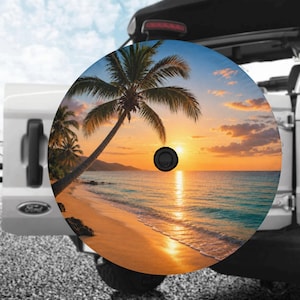 May include: A circular spare tire cover featuring a vibrant sunset beach scene with a palm tree leaning over the sand, turquoise ocean waves, and a golden sky. The cover has a black center hole and is mounted on the back of a white vehicle.