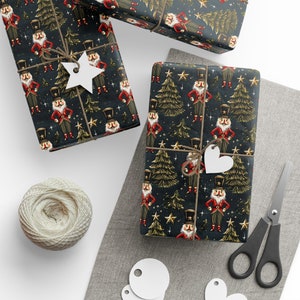 May include: Gift-wrapped presents with a festive design featuring nutcrackers, Christmas trees, and stars on a dark background. The gifts are tied with twine and adorned with white tags. A ball of twine and scissors are also visible.