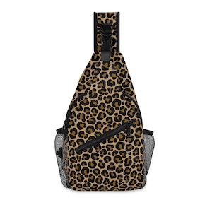 Puede incluir: Una bandolera con estampado de leopardo con cremallera negra, bolsillos laterales de malla negra y una correa ajustable negra. La bolsa presenta un patrón repetido de manchas marrones sobre un fondo beige.