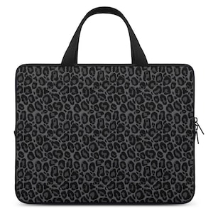 Puede incluir: Funda para portátil negra con diseño de estampado de leopardo gris. La funda tiene una cremallera y un asa.
