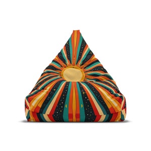 Könnte beinhalten: Ein dreieckiger Sitzsack mit einem Retro-Sonnenstrahlen-Design in Orange-, Gelb-, Rot-, Türkis- und Schwarztönen. Der Sitzsack hat eine große Sonne mit strohähnlicher Textur in der Mitte.