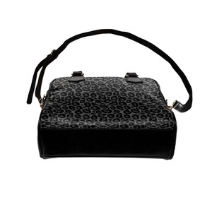 May include: A black handbag with a grey leopard print design. The bag has a top handle and a shoulder strap.