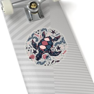 May include: A gray and white skateboard with a circular sticker featuring a pink and blue sea turtle surrounded by sea life, including starfish, seashells, and fish.