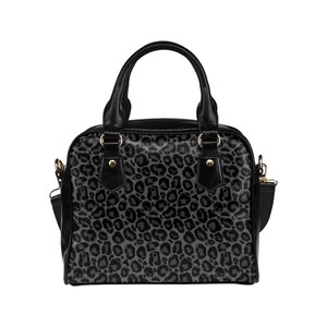 May include: A black handbag with a grey leopard print design. The bag has a top handle and a shoulder strap.