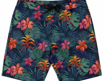 May include: Blue swim trunks with a tropical print featuring green leaves, pink and orange flowers, and yellow accents.