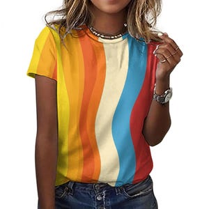 Può includere: Una maglietta a maniche corte con un motivo a righe colorate. Le righe sono ondulate e assomigliano a un arcobaleno.