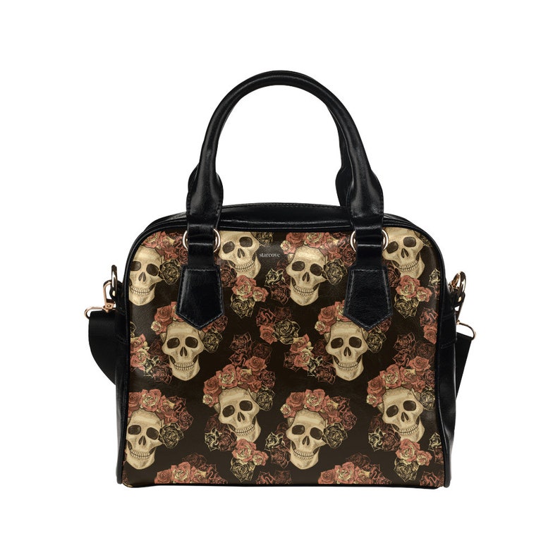 May include: Black handbag with a floral skull pattern. The skulls are surrounded by pink and orange roses.