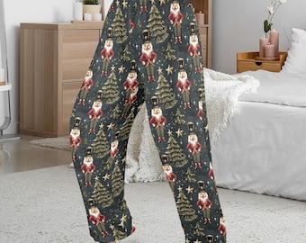 May include: Dark gray pajama pants with a repeating pattern of nutcrackers, Christmas trees, and stars. The nutcrackers are dressed in red and black uniforms. The trees are gold, and the stars are yellow. The pants are made of a soft, flowing fabric.