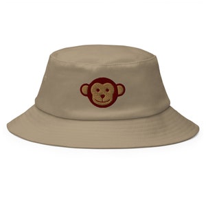 May include: A khaki bucket hat with a red embroidered monkey face.