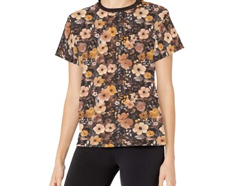 May include: A short-sleeved t-shirt with a black crew neck and a floral pattern. The pattern features various flowers in shades of yellow, orange, and brown against a dark background. The shirt is made of a soft material.