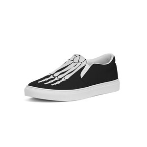 May include: Black slip-on canvas shoes with a white skeleton foot design.