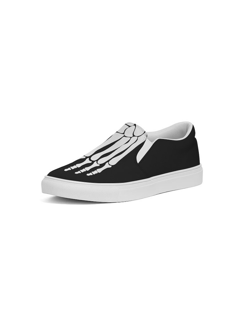 May include: Black slip-on canvas shoes with a white skeleton foot design.