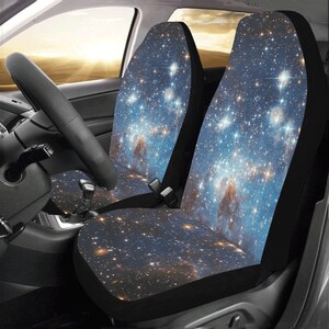 May include: Two black car seat covers with a galaxy print featuring a blue background with white and yellow stars.