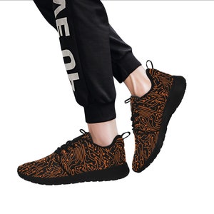 May include: Black sneakers with an orange circuit board pattern. The shoes have a white sole and a black lace.