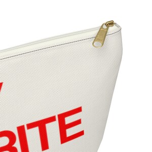 May include: A white canvas zippered pouch with the word "WRITE" in red letters.
