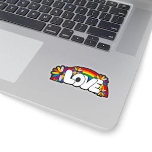 May include: A sticker with a rainbow and flowers surrounding the word "LOVE" in white letters.