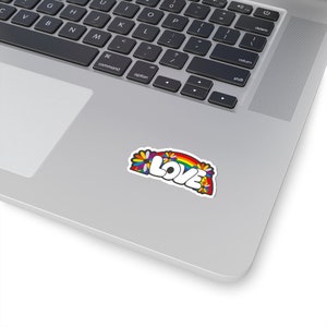 May include: A sticker with a rainbow and flowers surrounding the word "LOVE" in white letters with a black outline.
