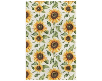 Op de afbeelding: Rechthoekig decoratief vloerkleed met een herhalend patroon van aquarel zonnebloemen. De zonnebloemen hebben gele bloemblaadjes, bruine centra en groene bladeren. De achtergrond is lichtbeige.