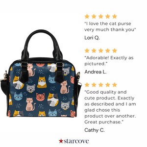 May include: A black handbag with a blue background and a pattern of colorful cartoon cats. The bag has a top handle and a shoulder strap.